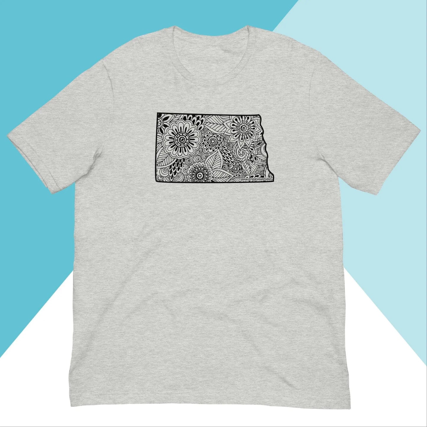 Gray North Owl Apparel North Dakota Floral Mandala Unisex Shirt with a black outlined state design on the chest, featuring intricate floral mandala patterns over a diagonally split blue and white background to express state pride.