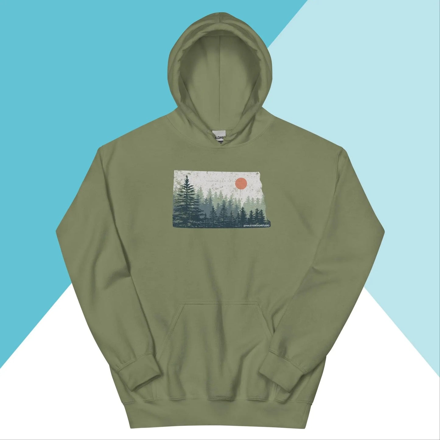The North Owl Apparels North Dakota Pine Trees Distressed Unisex Hoodie is olive green with a pine tree design, featuring a graphic of a forest and an orange sun on the chest against a blue and white retro background.